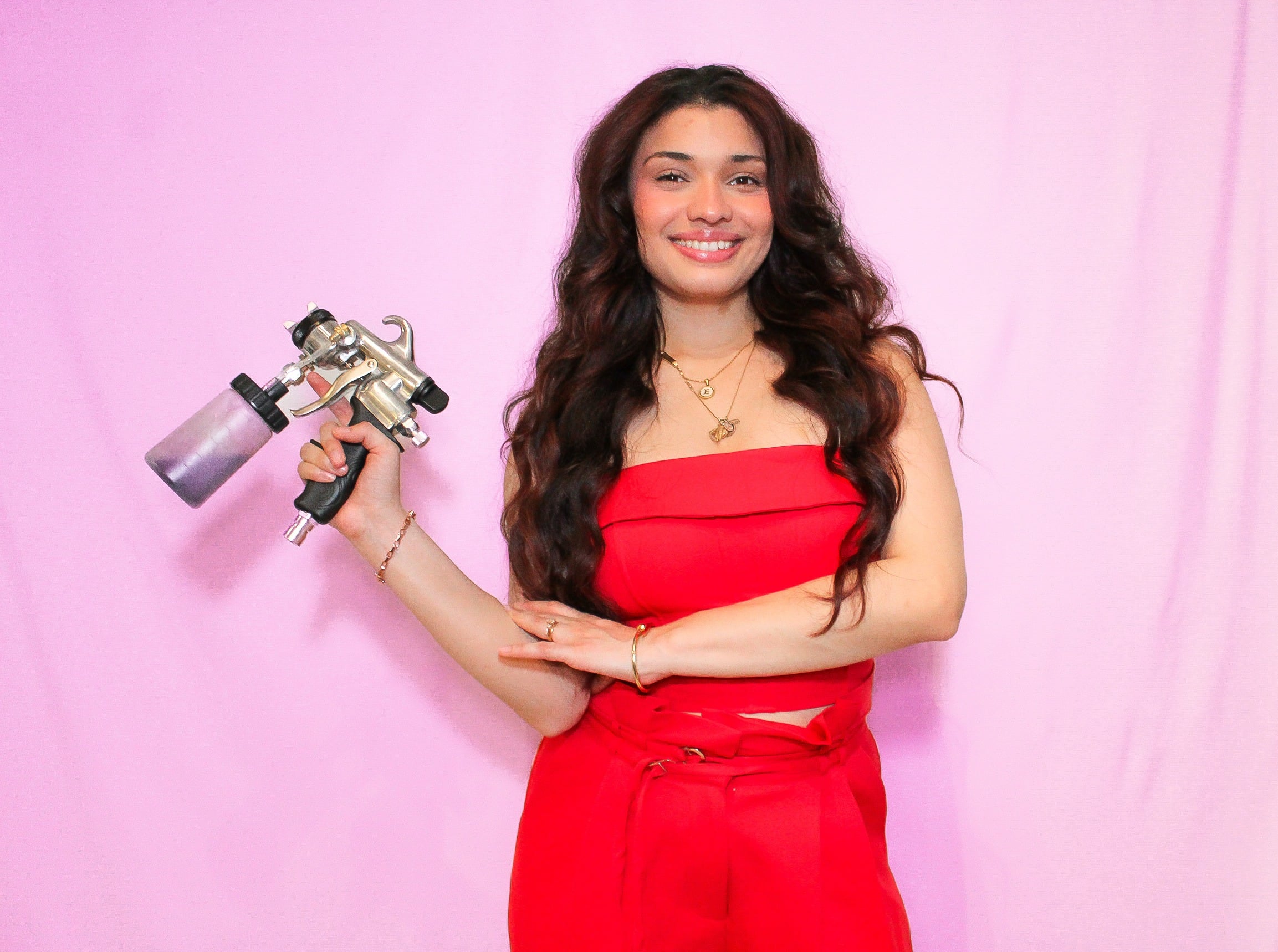 Estefany Costa holding a professional spray tan applicator